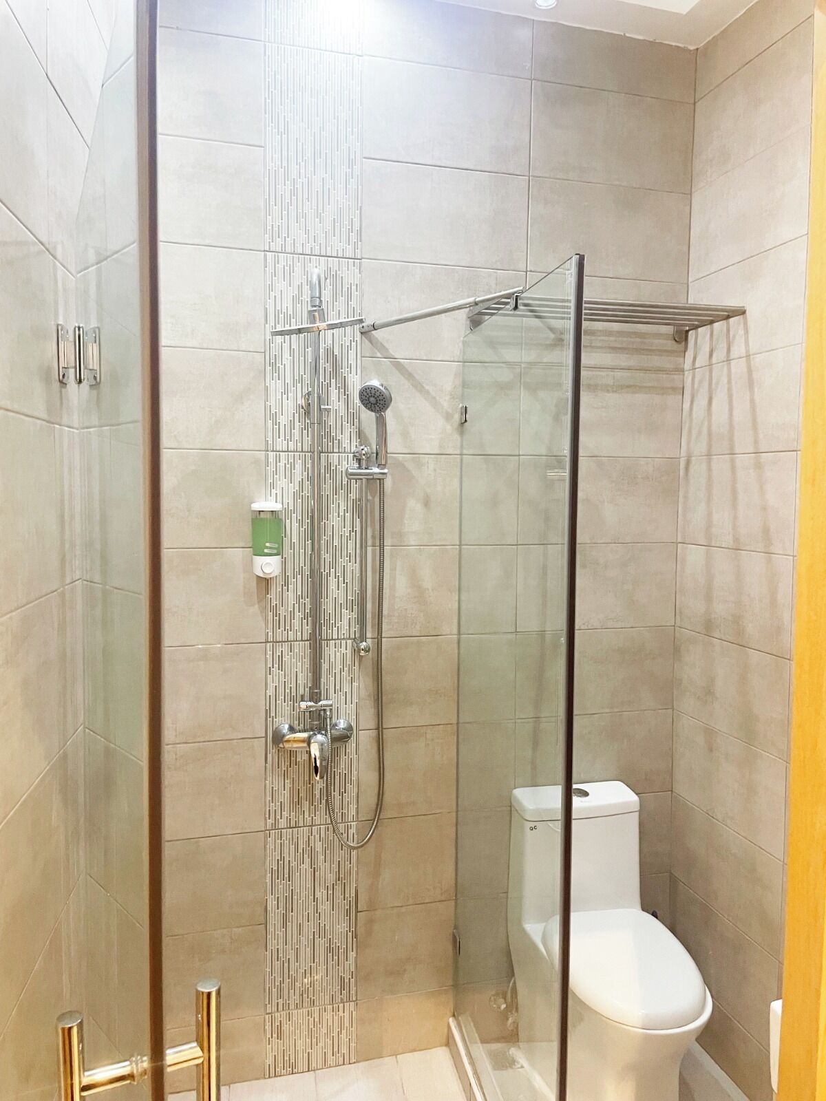 A modern bathroom with a glass-enclosed shower, a toilet, and a glass door.