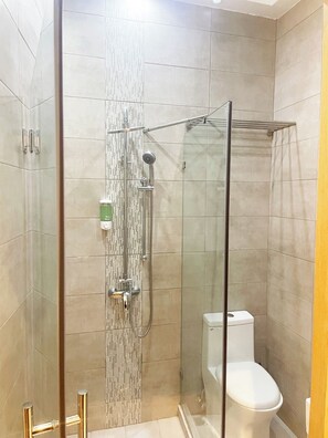 A modern bathroom with a glass-enclosed shower, a toilet, and a glass door. - City Caribbean Hotel Boutique (Santo Domingo)