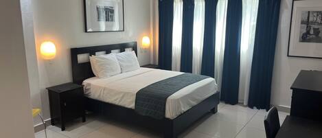 A neatly arranged bedroom with a bed, a ceiling fan, and a nightstand with a lamp.
