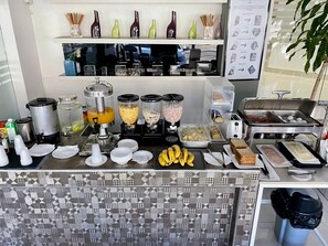 A breakfast buffet with various food items, a coffee station, and a display of decorative vases. - City Caribbean Hotel Boutique (Santo Domingo)