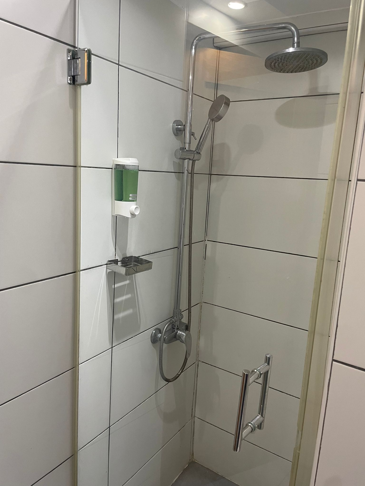 A modern shower with a handheld showerhead and a wall-mounted faucet.