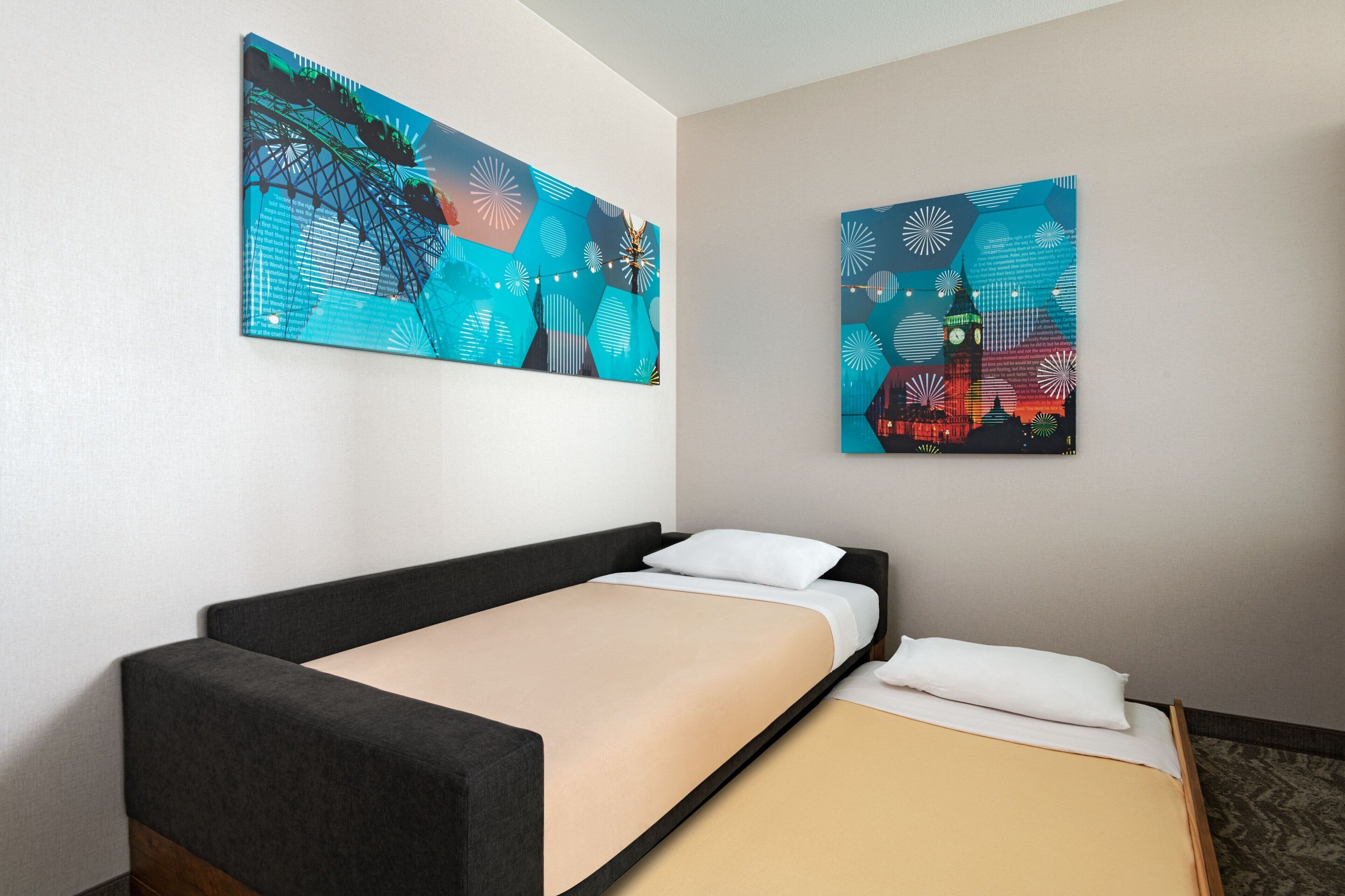 A hotel room with a single bed, a nightstand, and two large abstract paintings on the wall.