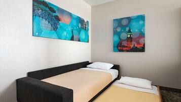 A hotel room with a single bed, a nightstand, and two large abstract paintings on the wall.
