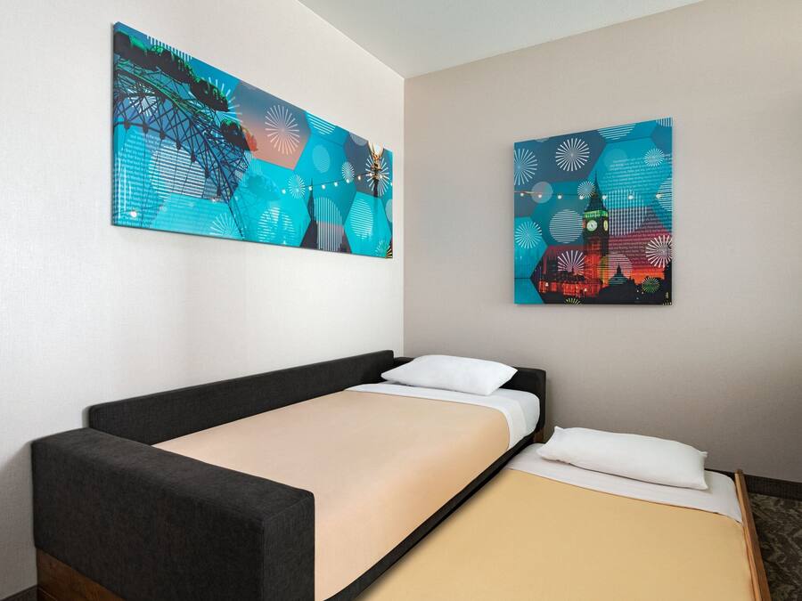 A hotel room with a single bed, a nightstand, and two large abstract paintings on the wall.
