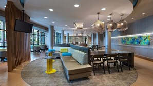 A modern lobby with a curved seating area, a bar, and a large artwork on the wall. - SpringHill Suites Anaheim Maingate (Anaheim)
