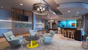 A modern lobby with seating, a bar area, and a large screen. - SpringHill Suites Anaheim Maingate (Anaheim)