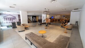 A spacious lobby with seating areas, a reception desk, and a staircase leading to other floors. - Hotel Plaza Genova Centro (Guadalajara)