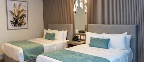 Habitación de hotel con dos camas, una mesita de noche con un teléfono, un espejo y una lámpara fijada a la pared.
