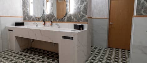 Un baño con piso de cuadros, un tocador de mármol con espejo y una puerta de madera.