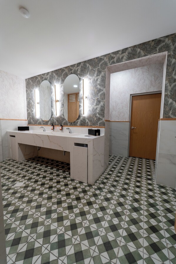 Un baño con piso de cuadros, un tocador de mármol con espejo y una puerta de madera.