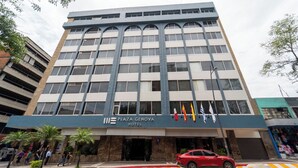 A multi-story hotel with a modern facade, a prominent entrance, and several flags. - Hotel Plaza Genova Centro (Guadalajara)