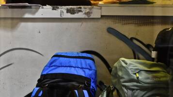 A person at a counter with a computer, surrounded by bags and a wall with graffiti.