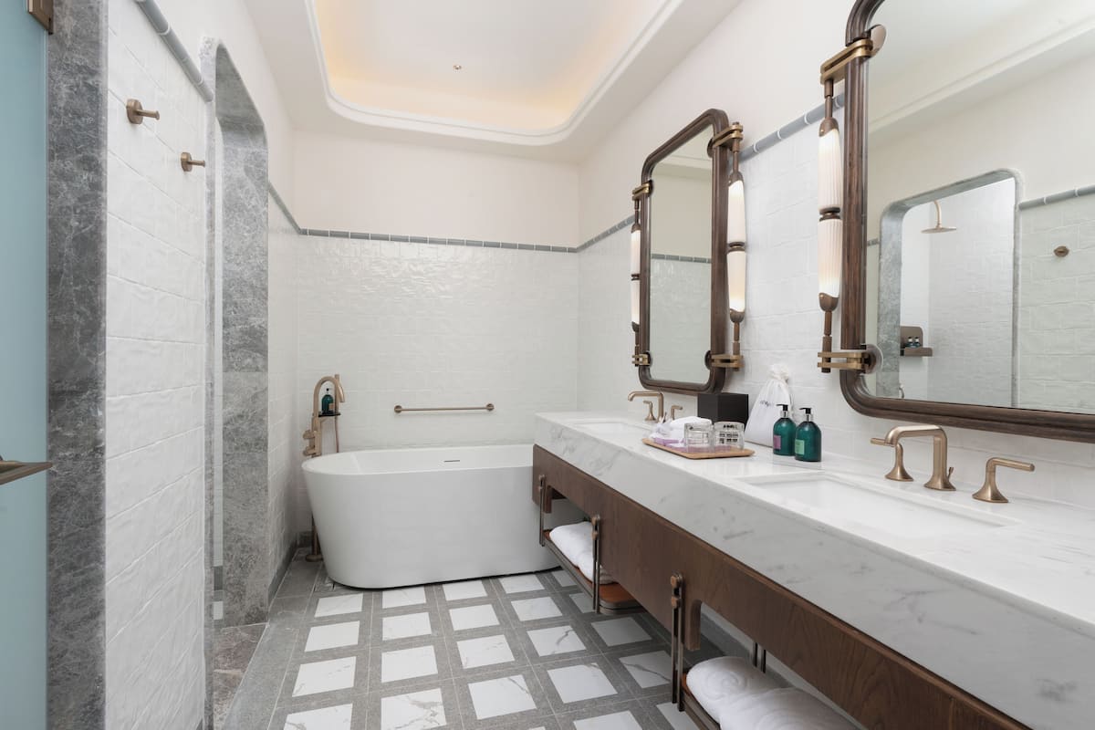 A modern bathroom with a freestanding bathtub, a vanity with a large mirror, and a tiled floor.