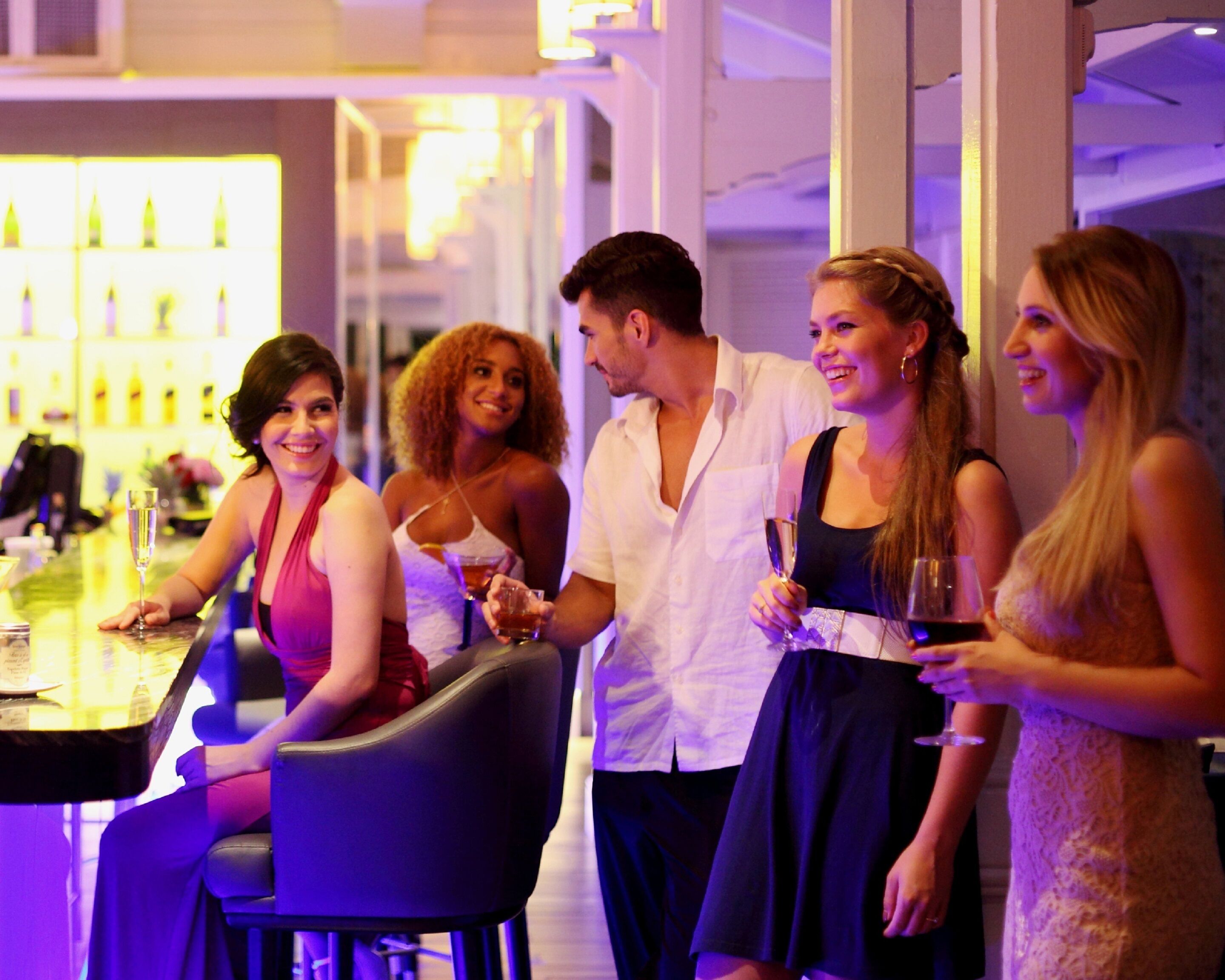 Un groupe de personnes se trouve dans un bar au décor moderne, comprenant un comptoir et un espace réservé aux clients.