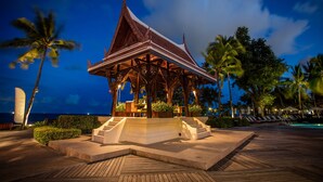 A traditional wooden pavilion with a sloped roof, surrounded by palm trees and a pool area. - Centara Grand Beach Resort Hua Hin (Hua Hin)