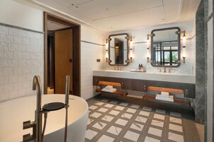 A modern bathroom with a large bathtub, two sinks, and a bench.