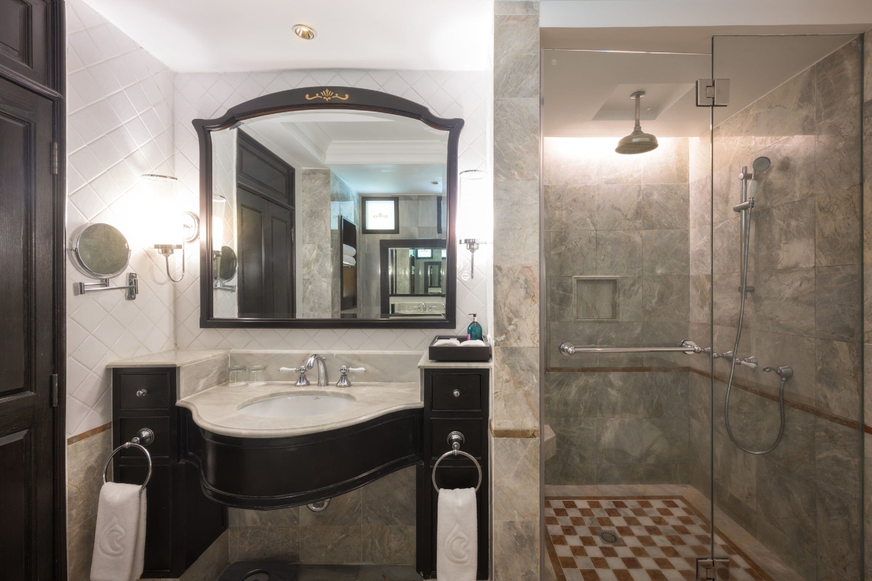 A bathroom with a large mirror, a sink, and a shower.