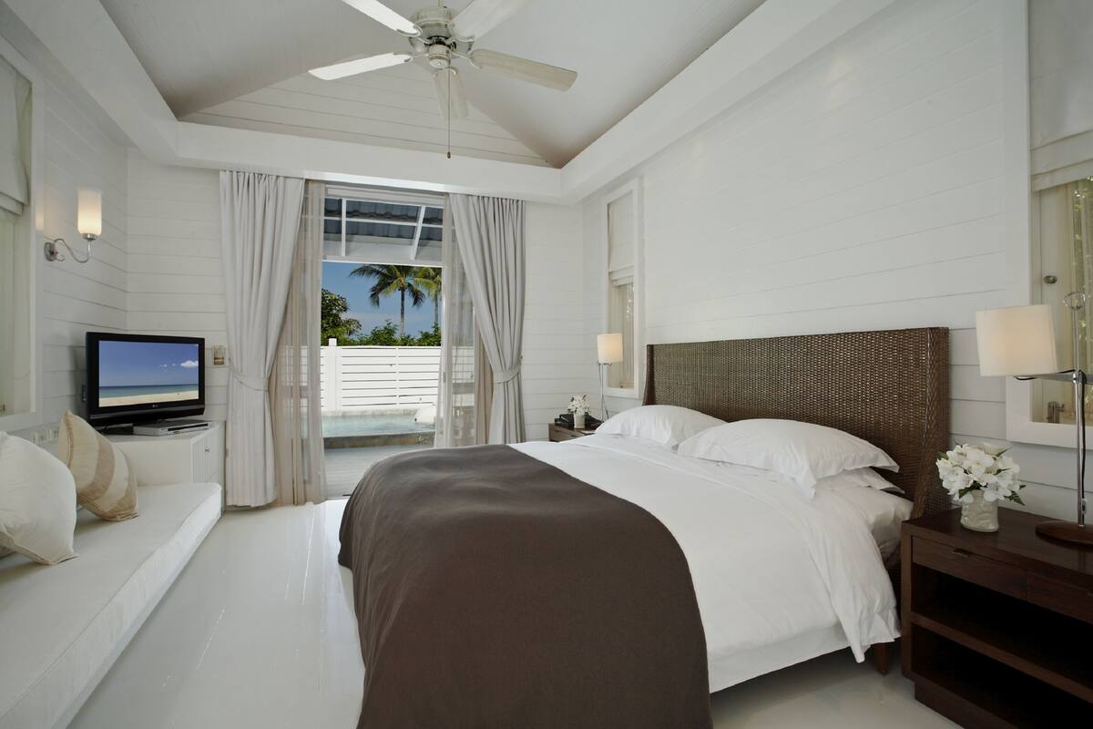 Ein Hotelzimmer mit Bett, Fernseher, Deckenventilator und Blick ins Freie.