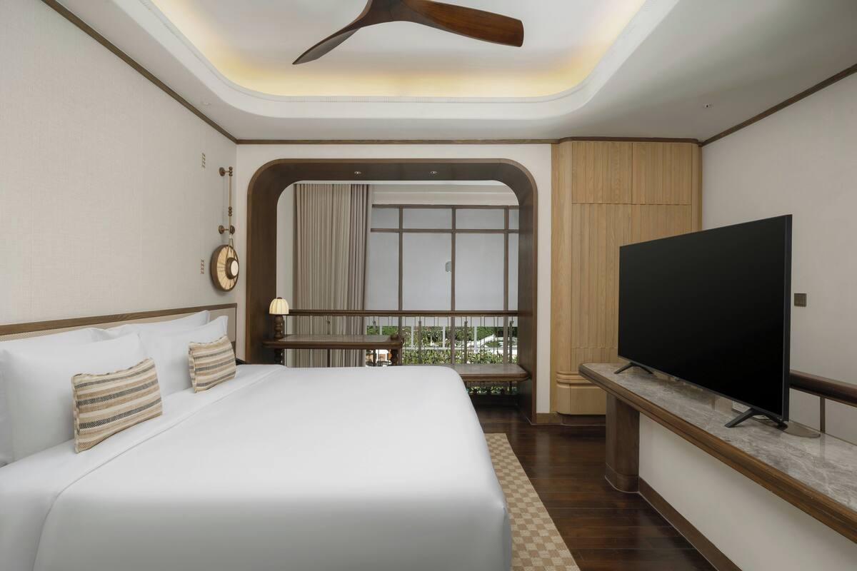 Ein Hotelzimmer mit Bett, Fernseher, Deckenventilator und Blick ins Freie.
