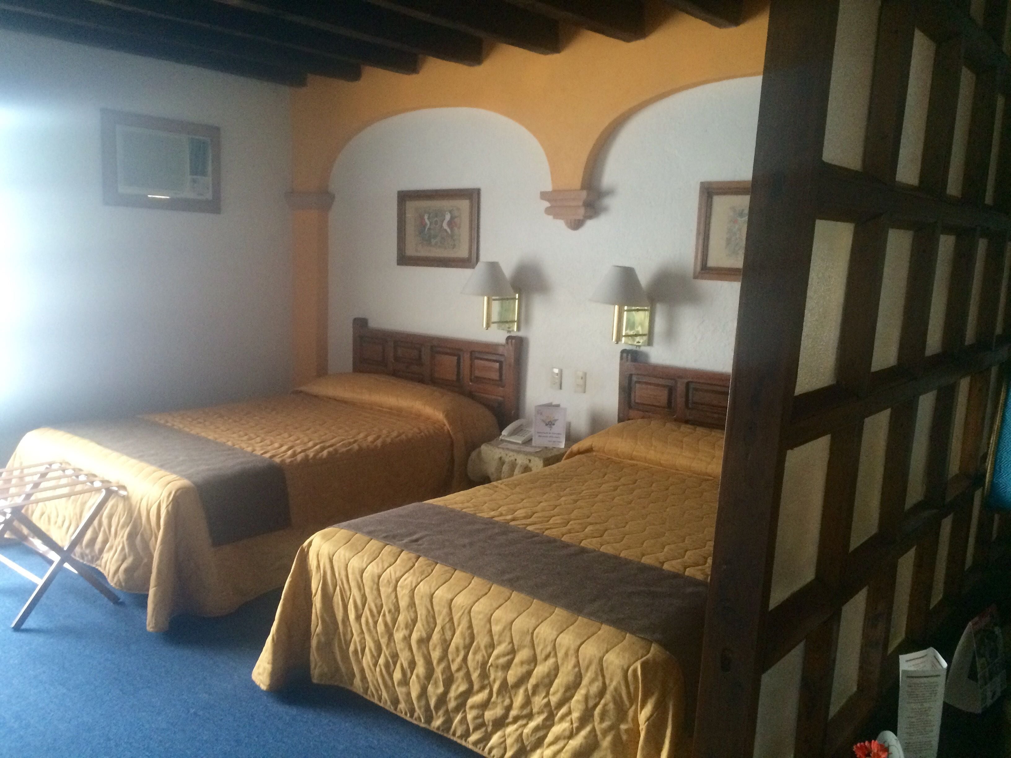 A hotel room with two beds, wooden headboards, and a blue carpet.