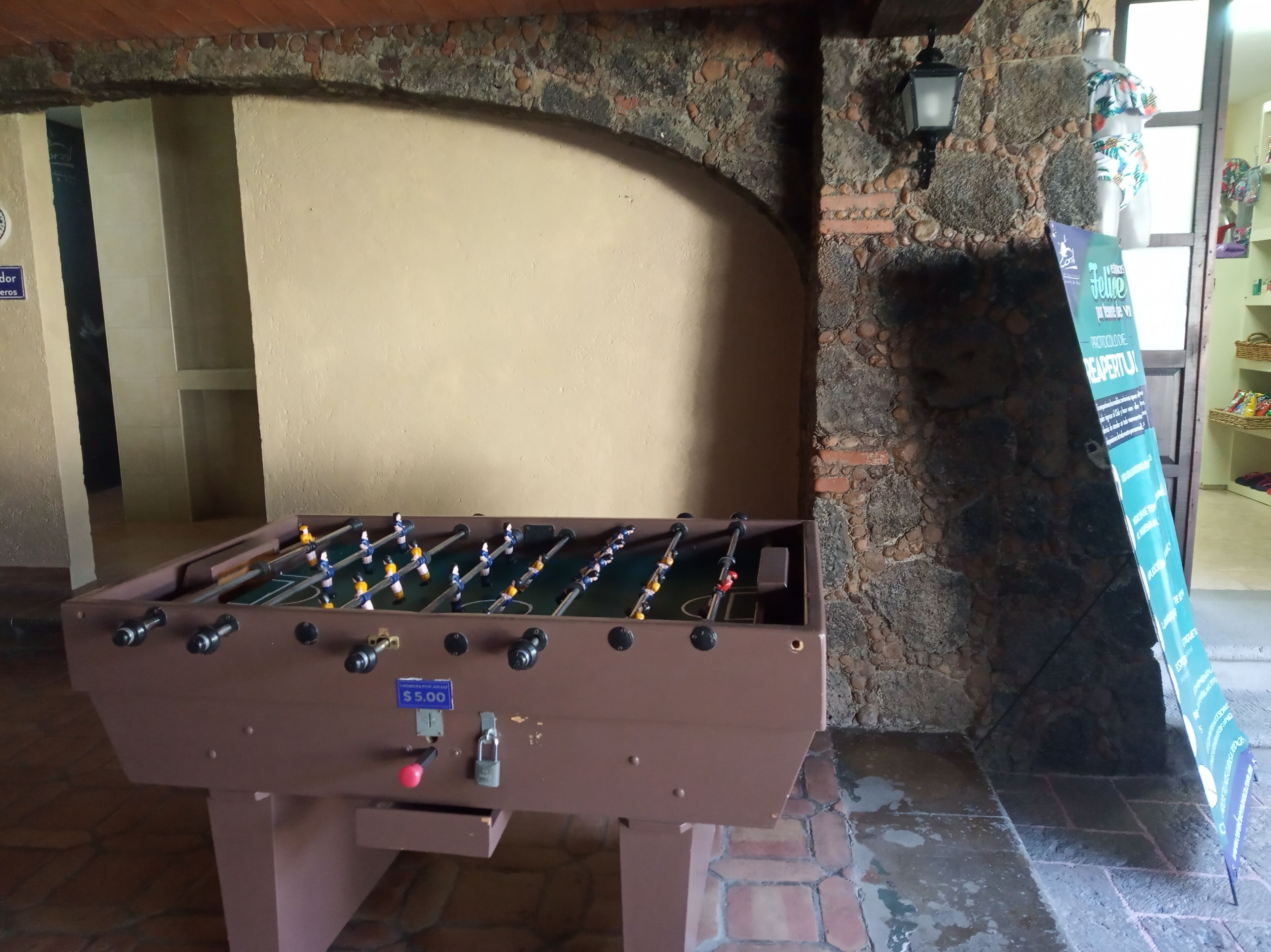 A foosball table in a room with a stone wall and a tiled floor.