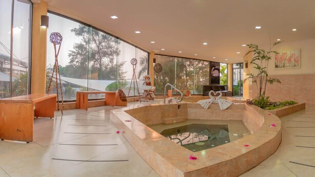 Un espace détente avec un jacuzzi, des bancs en bois et de grandes fenêtres donnant sur la forêt.