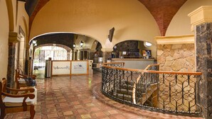 Un hall d’entrée spacieux, doté d’un escalier en colimaçon, de murs en pierre et d  ’un comptoir d’accueil.