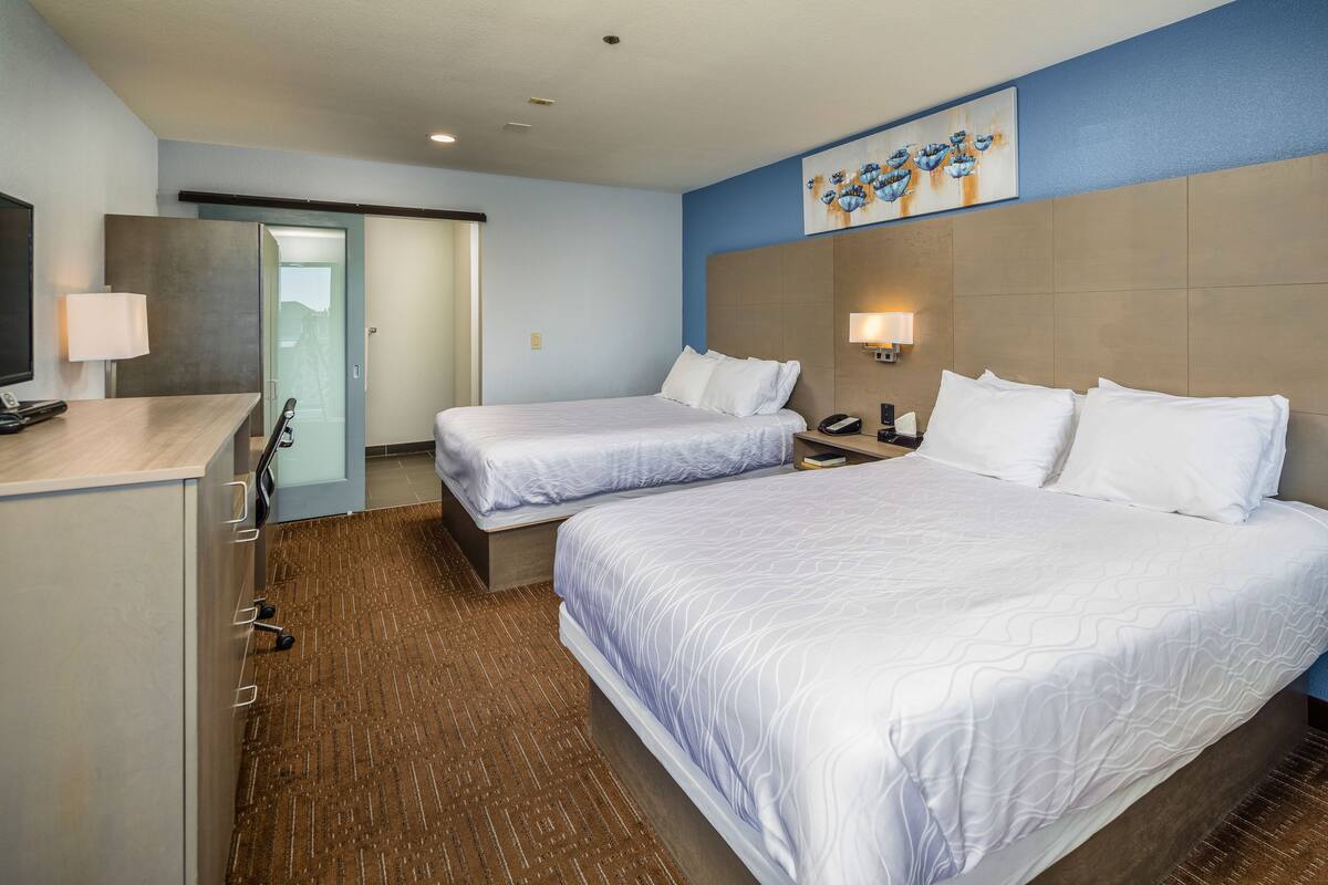 A hotel room with two beds, a desk, and a television.
