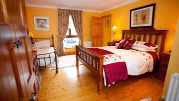 A bedroom with a wooden bed, a wooden dresser, a nightstand, and a window with curtains.