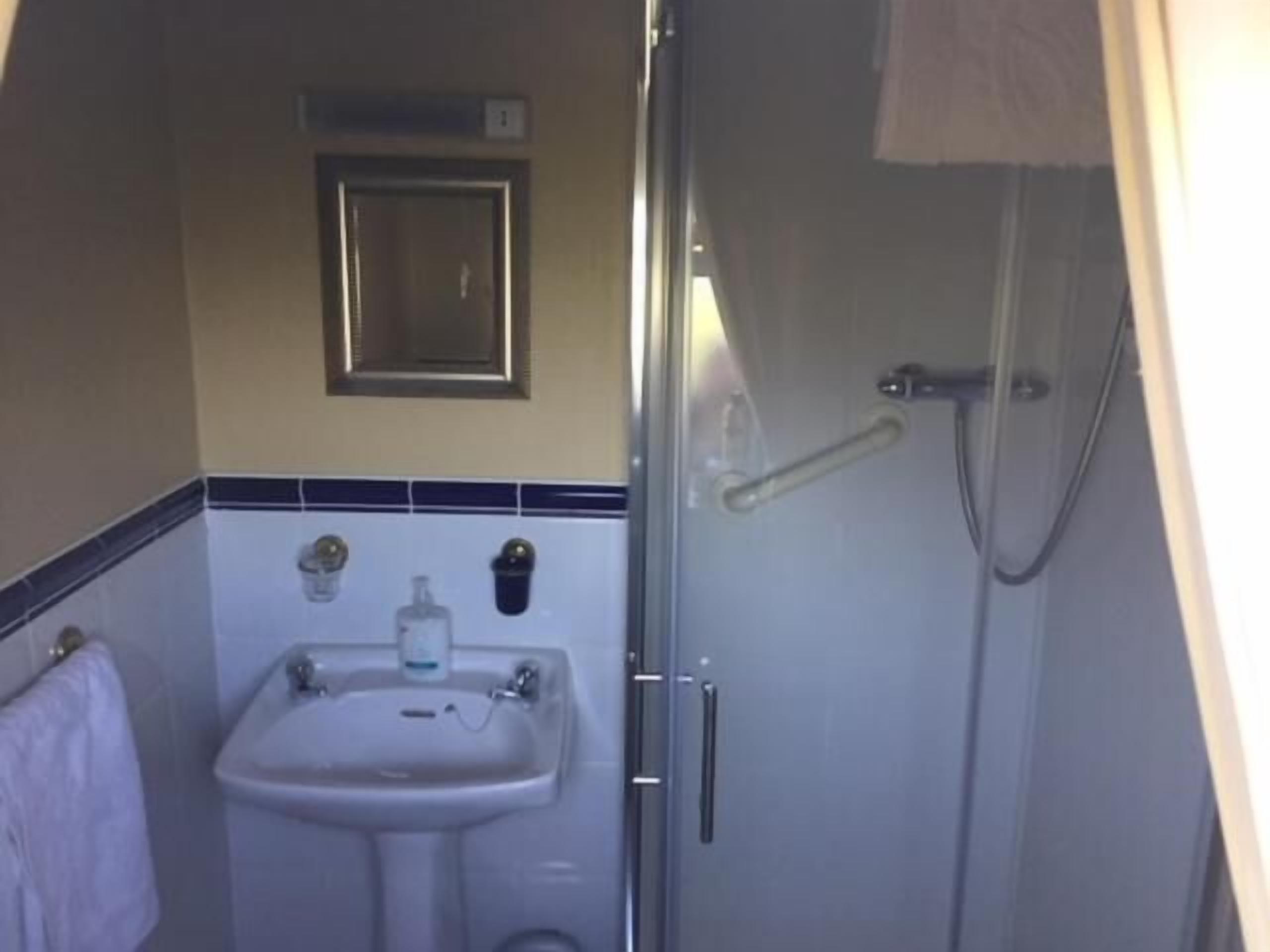 A compact bathroom with a sink, mirror, and shower.