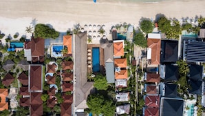 Luchtbeeld van een kustresort met meerdere gebouwen, een strand en boten.
