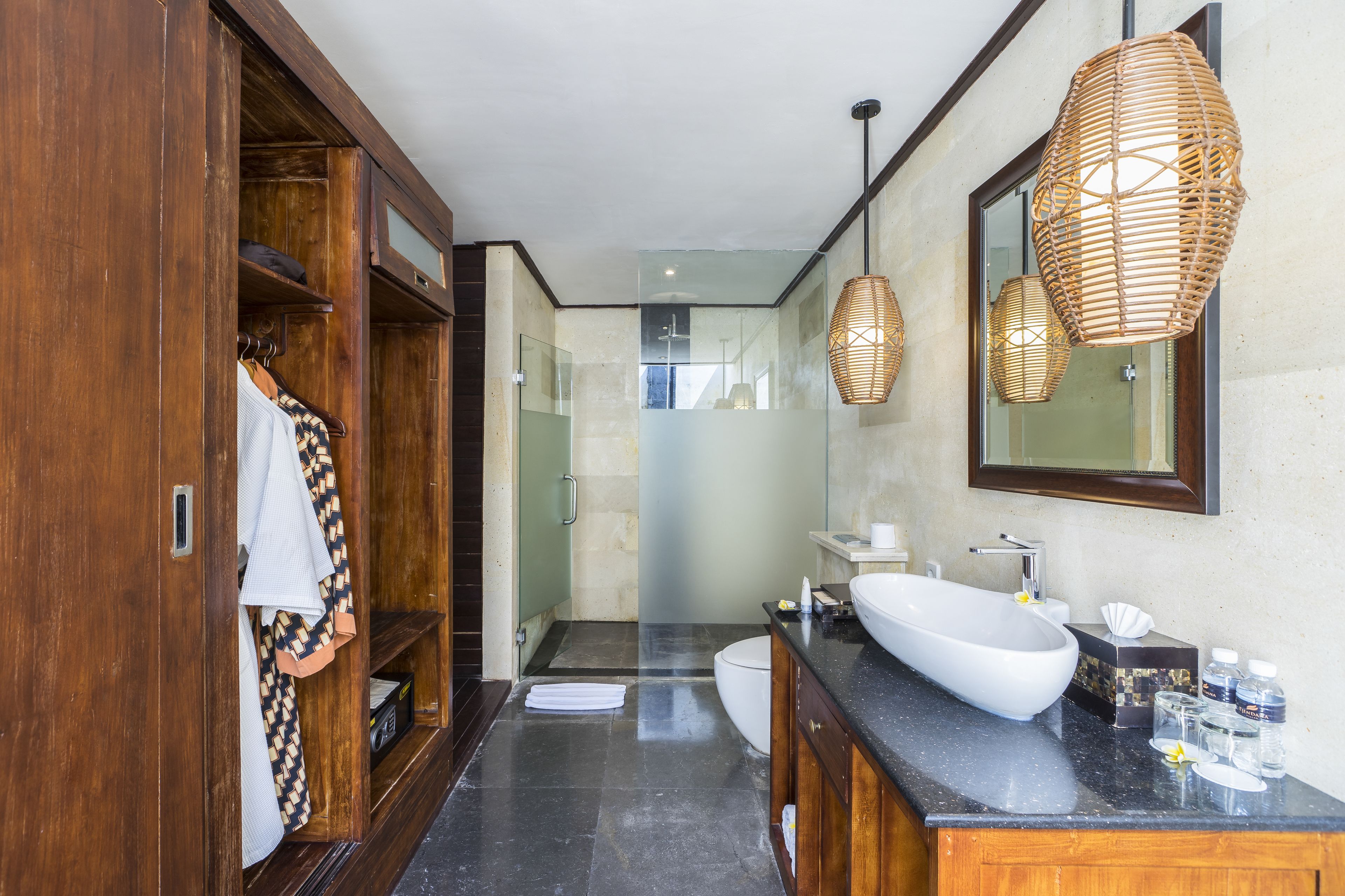 A modern bathroom with a large mirror, wooden cabinets, a white sink, and a shower area.