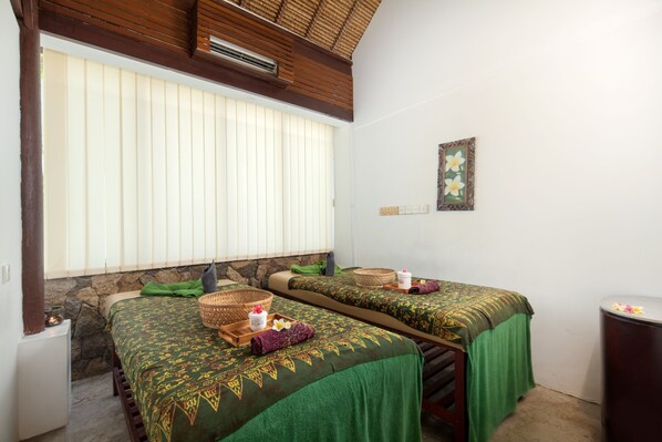 A room with two beds, each with a green bedspread and a woven basket on the side. There is a stone wall and a window with blinds. - Lembongan Beach Club and Resort (Lembongan Island)