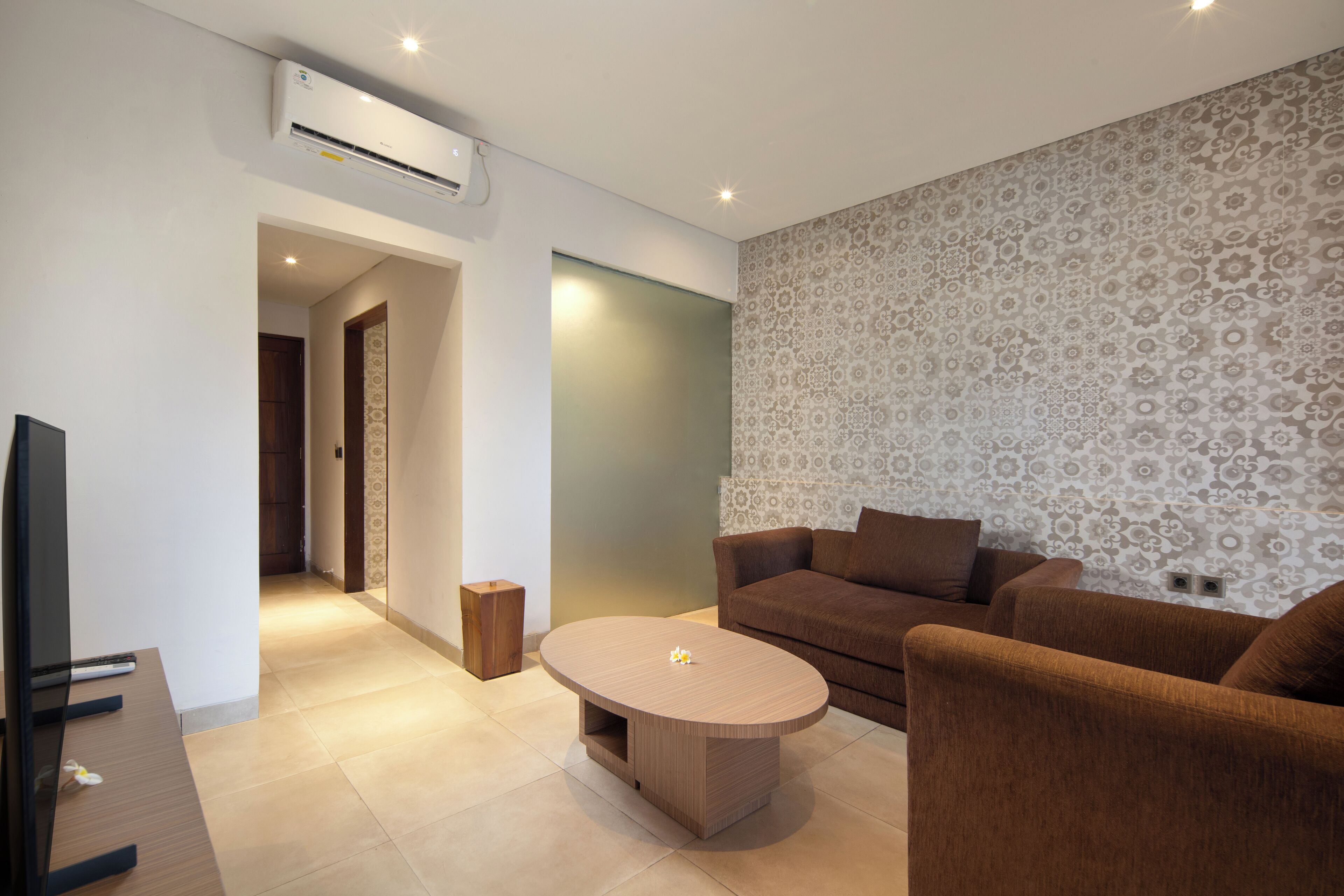 A modern living room with a brown sofa, a wooden coffee table, and a TV on a stand.