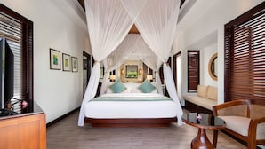 Um quarto espaçoso com uma cama grande, um espaço para sentar e uma escrivaninha de madeira.