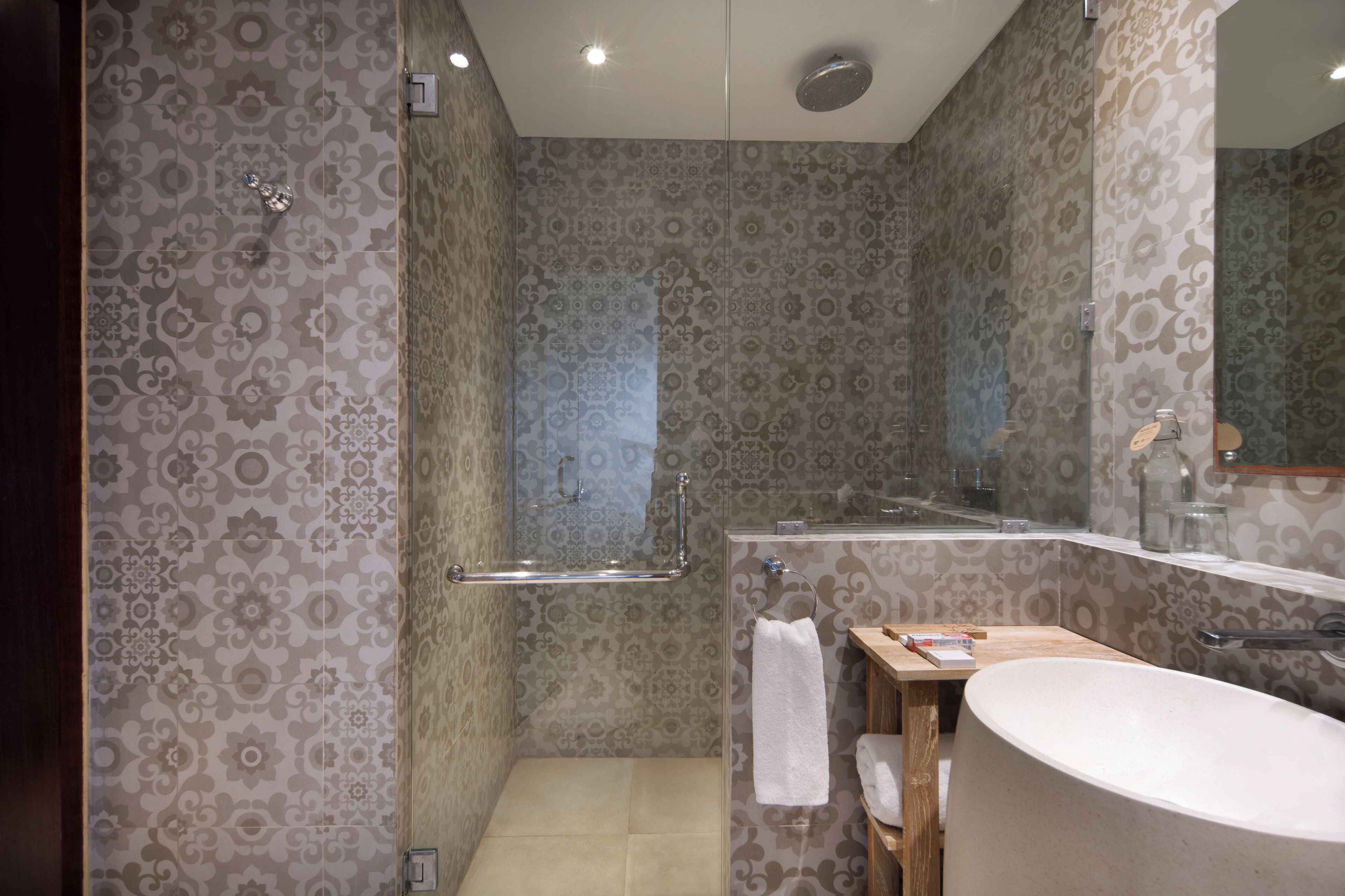 A bathroom with patterned wallpaper, a shower, a sink, and a mirror.