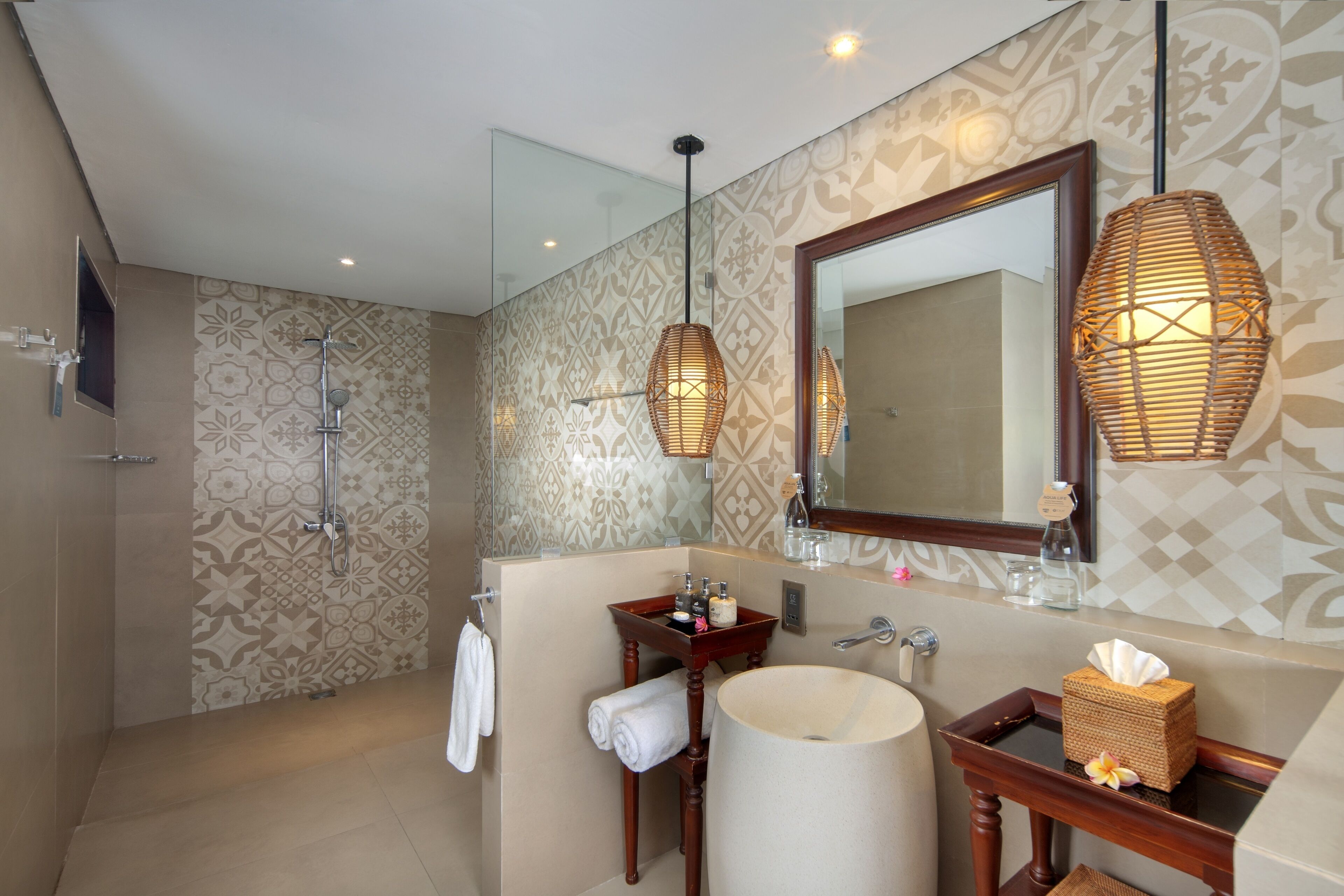 Une salle de bain moderne dotée d’une douche à parois de verre, d’un meuble-lavabo avec un grand miroir et d’un autre meuble-lavabo en bois avec un lavabo rond.
