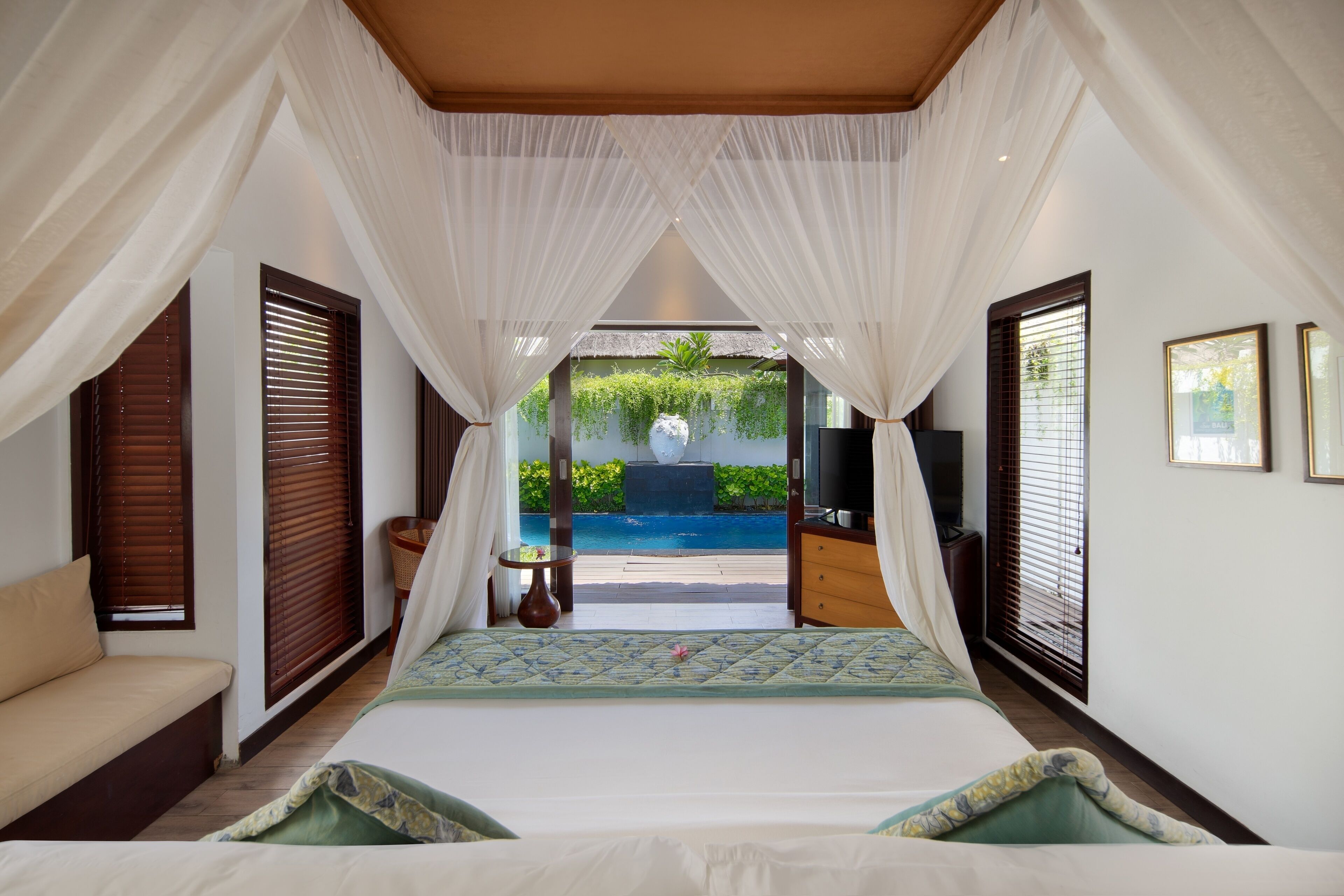 Une chambre avec un lit, un canapé, une télévision et une vue sur une piscine.