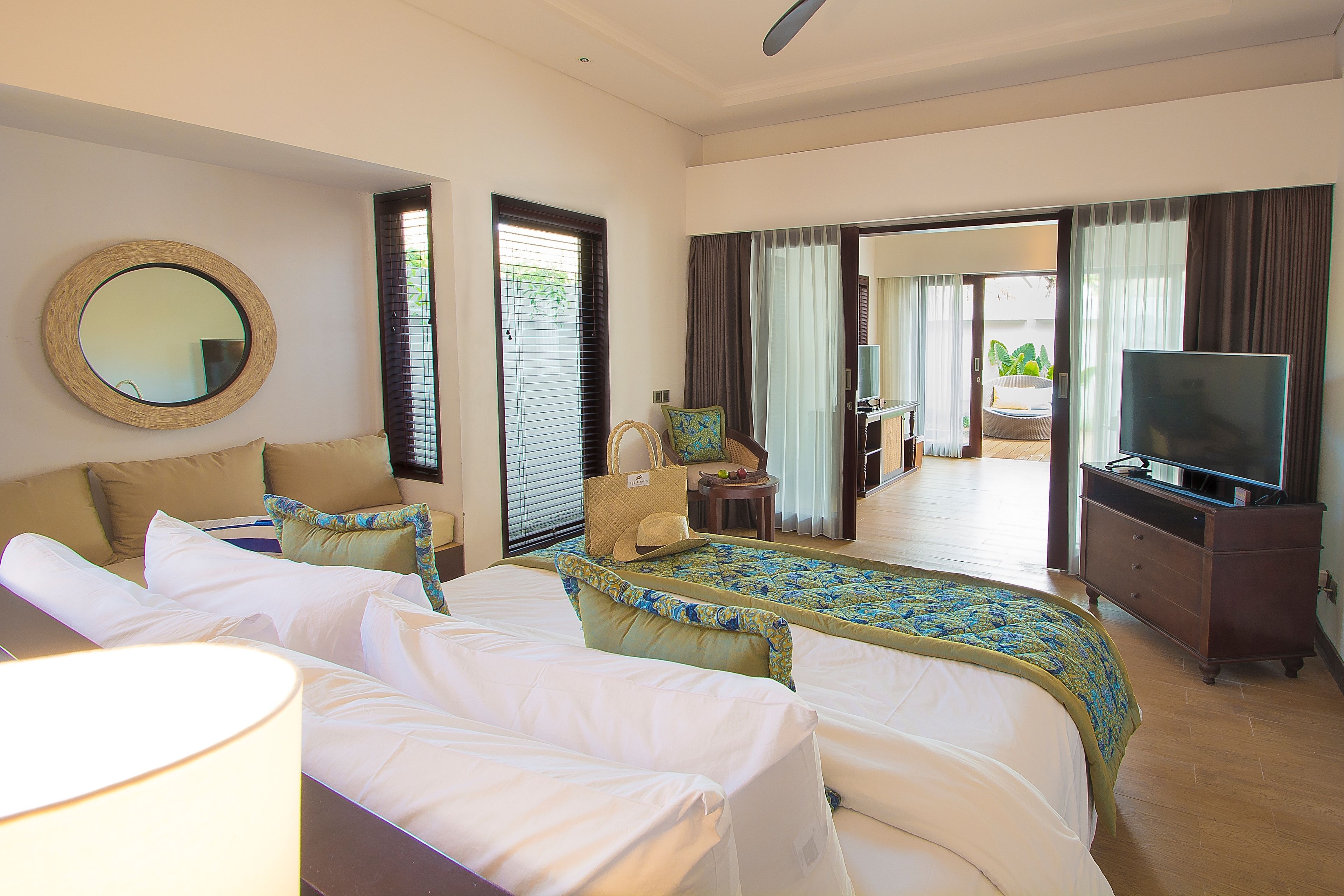 A hotel room with a large bed, a television, a desk, and a view of the outdoors.
