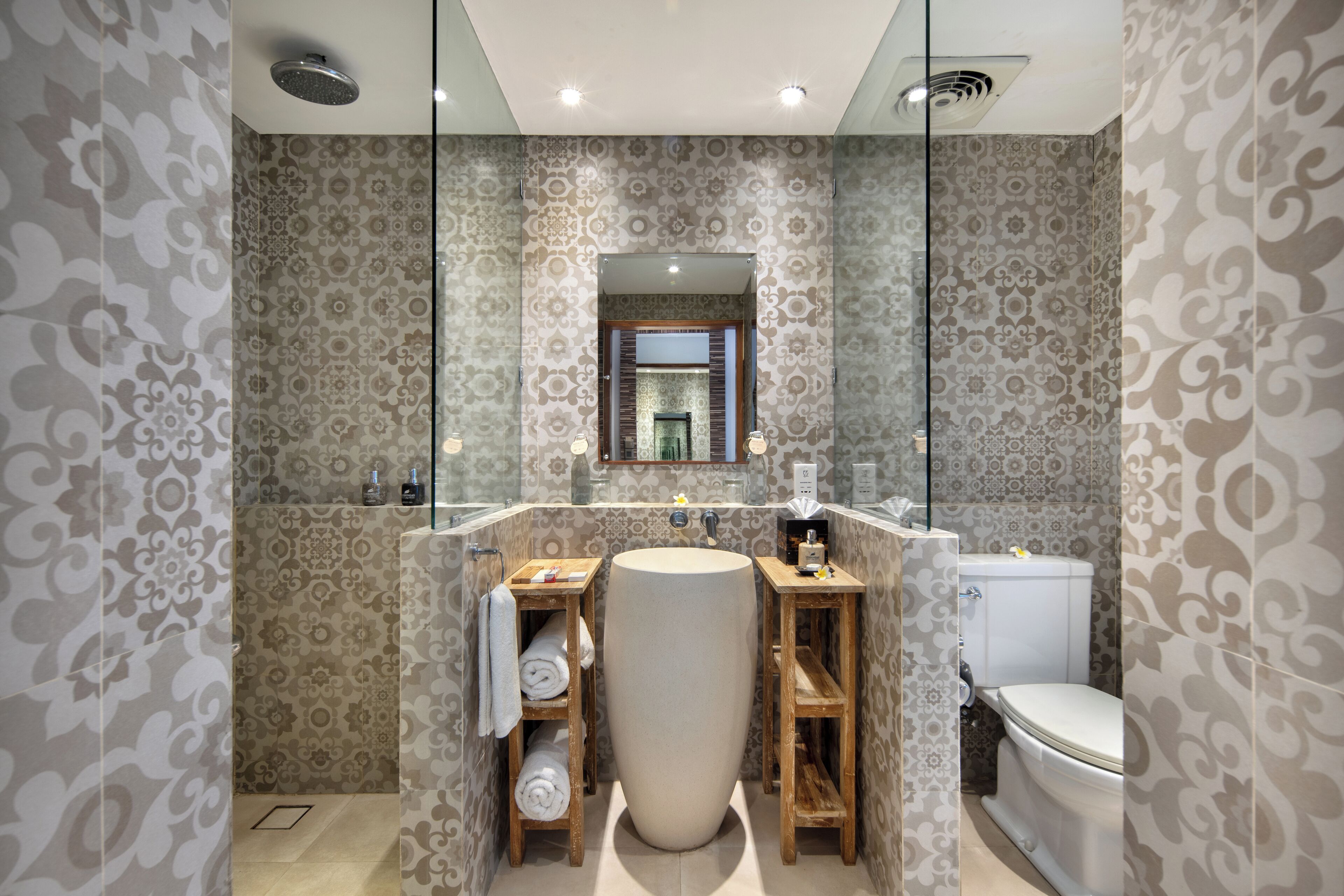 Un baño con paredes decoradas, un lavamanos amplio, repisas de madera y un inodoro.