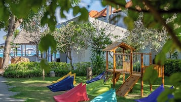 Relax in a serene outdoor space surrounded by lush greenery and a family-friendly play structure.
