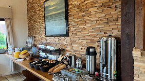 Un bufé de desayuno con diversos alimentos y bebidas, una máquina de café y un cuadro grande en la pared.