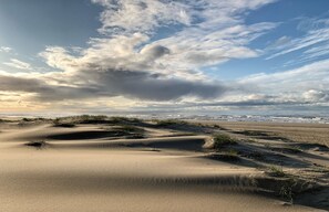 Una playa con dunas de arena y cielo nublado.