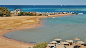 A coastal resort with clear waters, beach umbrellas, and a boat dock.