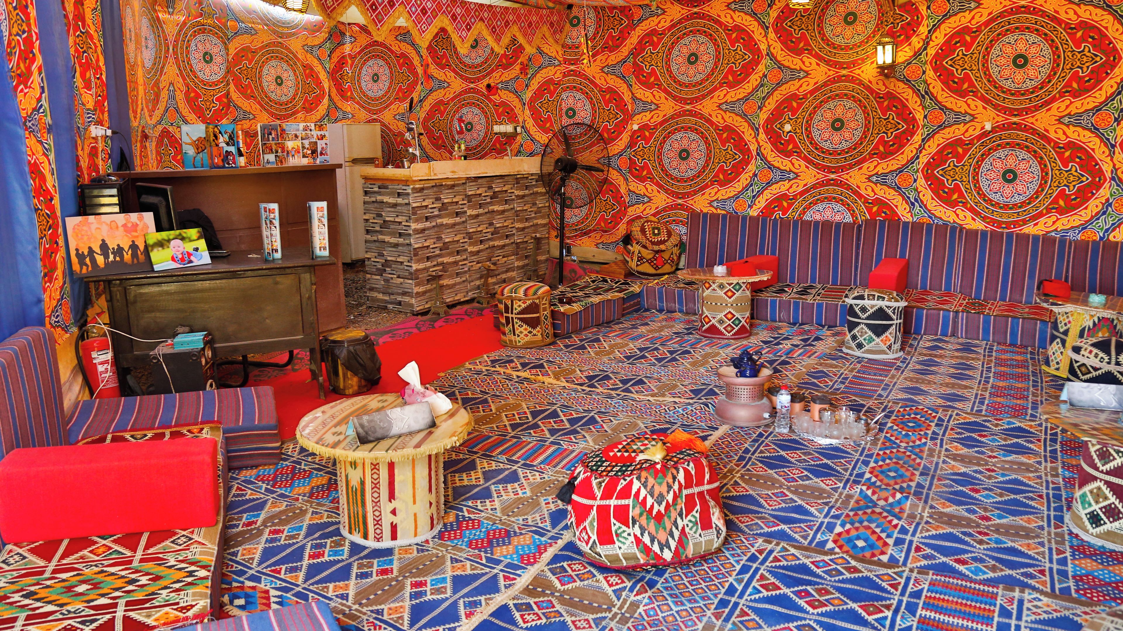 Une pièce avec un tapis à motifs, un canapé, une petite table et un mur orné de décorations complexes.