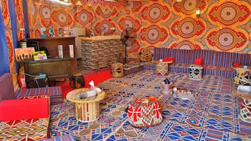 Quarto com carpete estampado, sofá, mesa pequena e parede com desenhos detalhados.