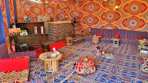 A room with a patterned carpet, a sofa, a small table, and a wall with intricate designs.