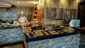 Zona de bufé con diversas opciones de comida y un chef preparando alimentos.