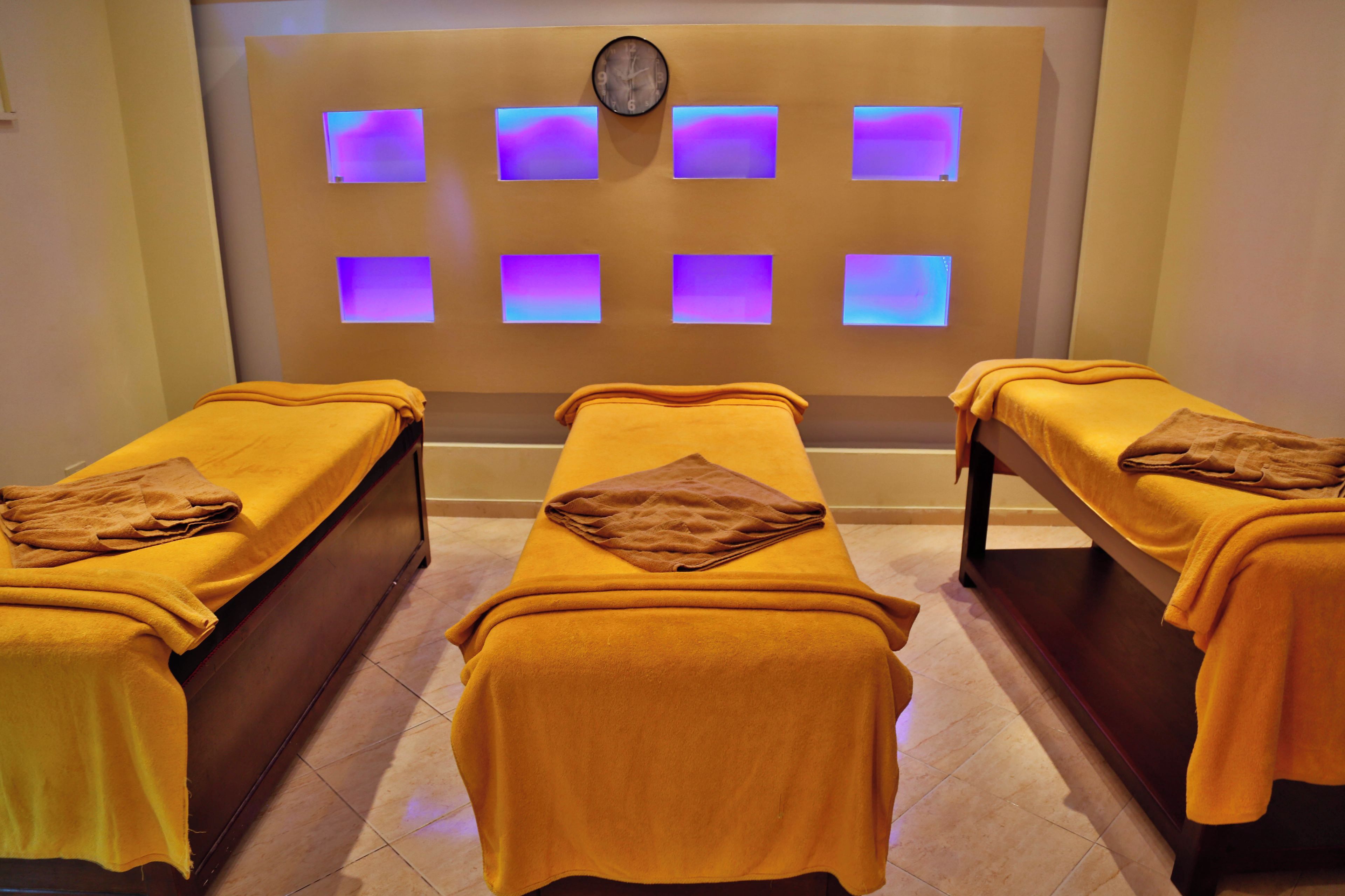 A room with three massage tables, each with a towel and a blanket.