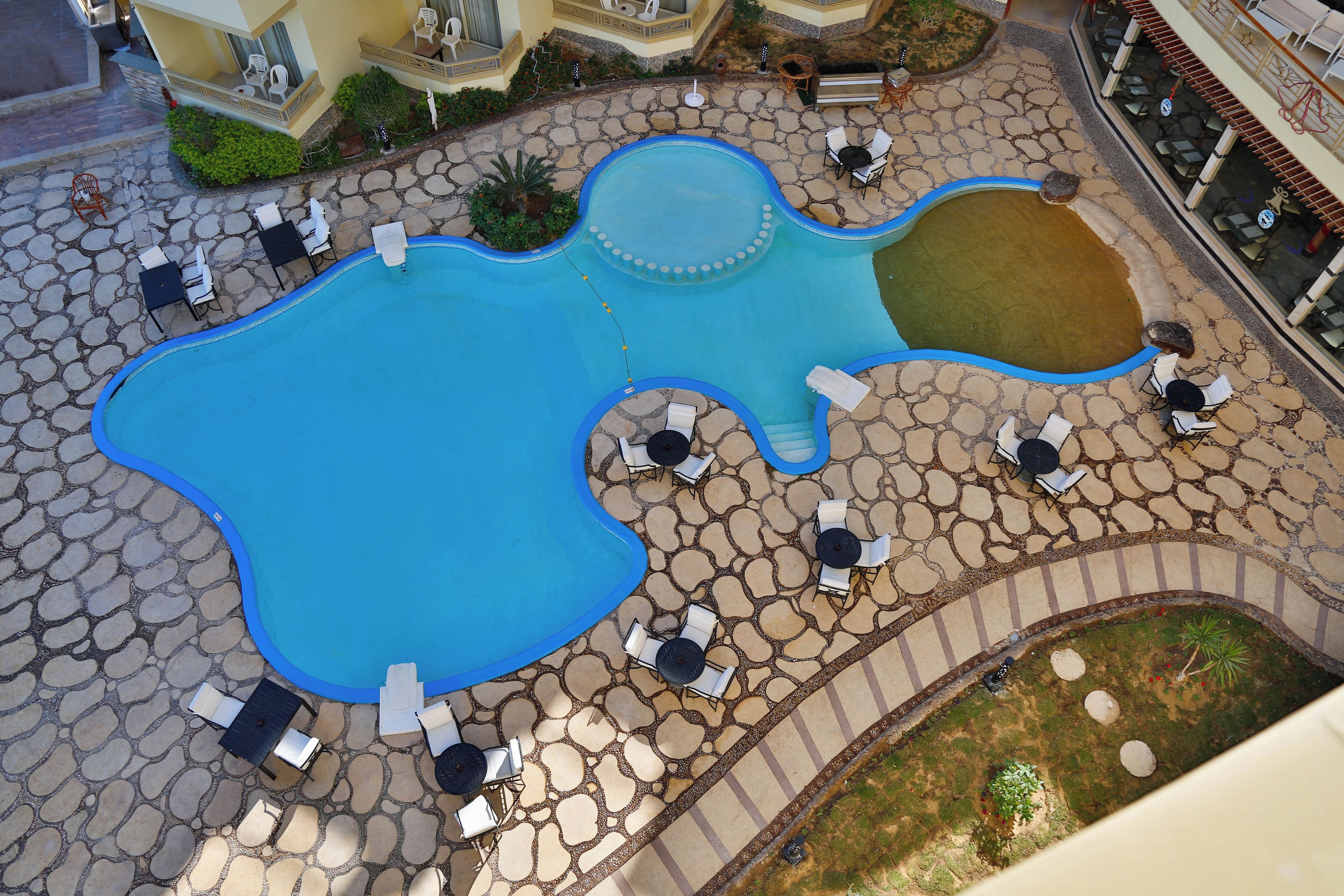 A pool area with multiple seating arrangements and a small water feature.